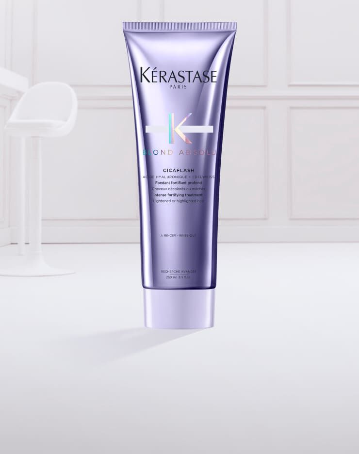 Un tubetto di prodotto per capelli Kerastase Blond Absole, con una consistenza cremosa e morbida di colore lilla che esce dal tappo.