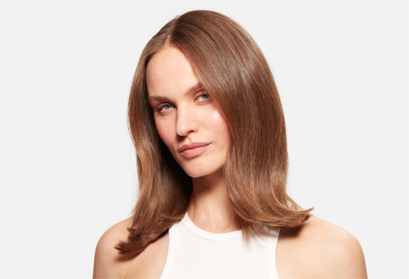 Ritratto di una donna con capelli castani di media lunghezza, lucidi e ben acconciati, su sfondo bianco.