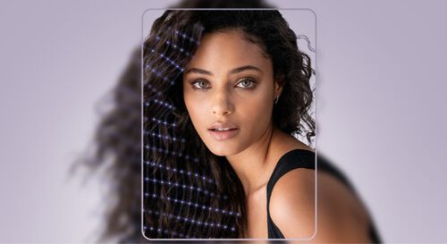 Immagine di una giovane donna con capelli ricci, che guarda verso l'obiettivo con un'espressione fiduciosa, sfondo sfumato in tonalita chiare.