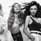 A group of five women smiling and posing playfully in a dynamic, black-and-white photo, showcasing diverse hairstyles and fashion styles.