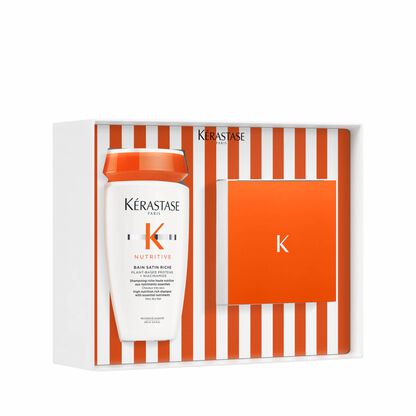 Scatola regalo Kerastase con shampoo Nutritive Bain Satin Riche e un accessorio, presentata su sfondo a righe arancioni e bianche.