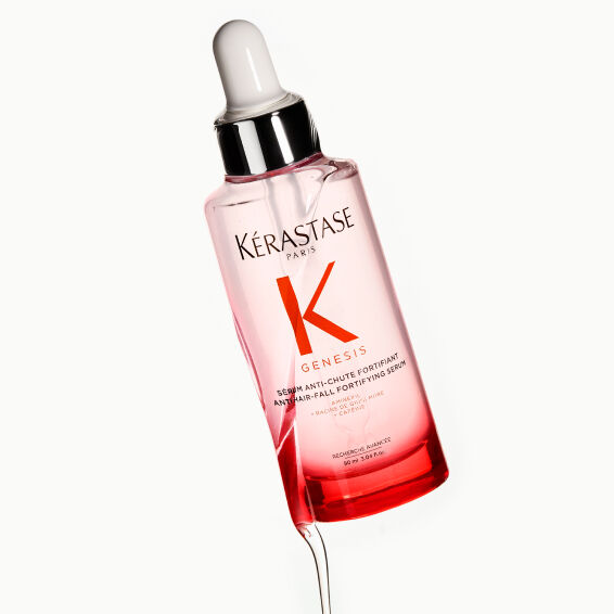 Donna con top rosso e capelli scuri e lisci, a illustrazione dell'efficacia del siero anticaduta Kerastase