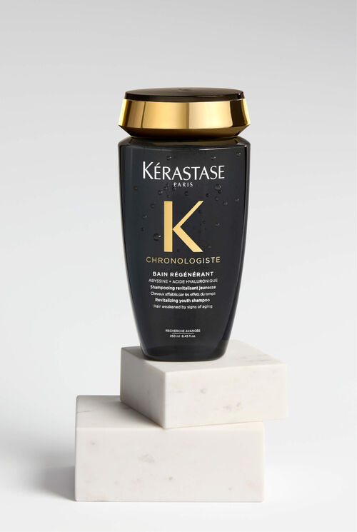 Shampoo Chronologiste nero e oro su un'elegante piattaforma di marmo.