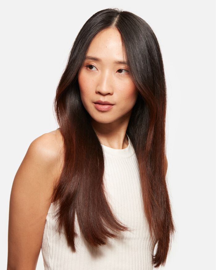 Ritratto di una donna con lunghi capelli castani e lisci, che indossa una maglietta bianca. Guarda leggermente di lato, con espressione serena.