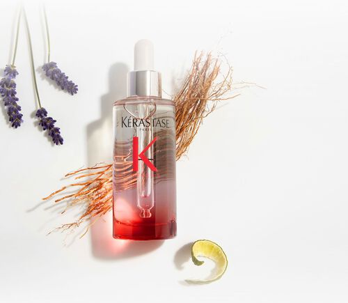 Bottiglia del siero Kerastase Genesis Serum Anti-Chute Fortifiant, circondata da elementi botanici come lavanda e zenzero.