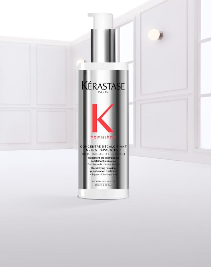 Flacone di siero per capelli Kerastase con gocce d'acqua che scivolano lungo la superficie.