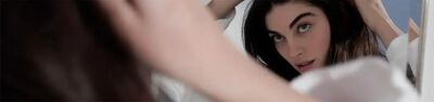 A close-up shot of a person brushing their hair in front of a mirror, with soft focus on their face and hand.