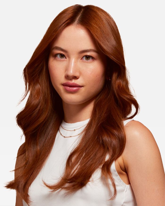 Ritratto di una giovane donna con lunghi capelli castani lucidi, che indossa una maglietta bianca e ha un'espressione serena.