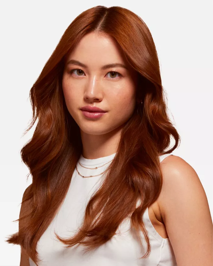 Ritratto di una giovane donna con lunghi capelli castani lucidi, che indossa una maglietta bianca e ha un'espressione serena.