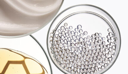 Immagine che mostra tre contenitori con diverse sostanze: un liquido trasparente, una crema bianca e delle piccole sfere trasparenti, su sfondo chiaro.