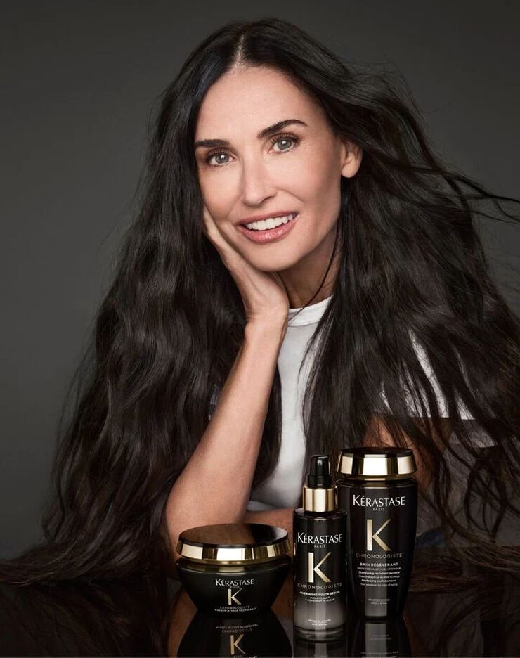 Demi Moore in posa con la linea per capelli Kerastase Chronologiste nelle confezioni nere e oro.