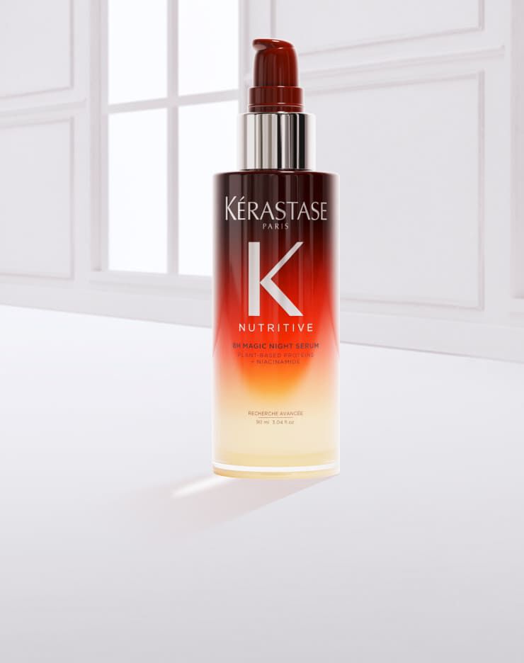 Flacone di siero per capelli Kerastase, con una goccia di prodotto accanto, su sfondo chiaro.