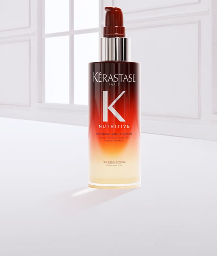 Flacone di siero per capelli Kerastase, con una goccia di prodotto accanto, su sfondo chiaro.