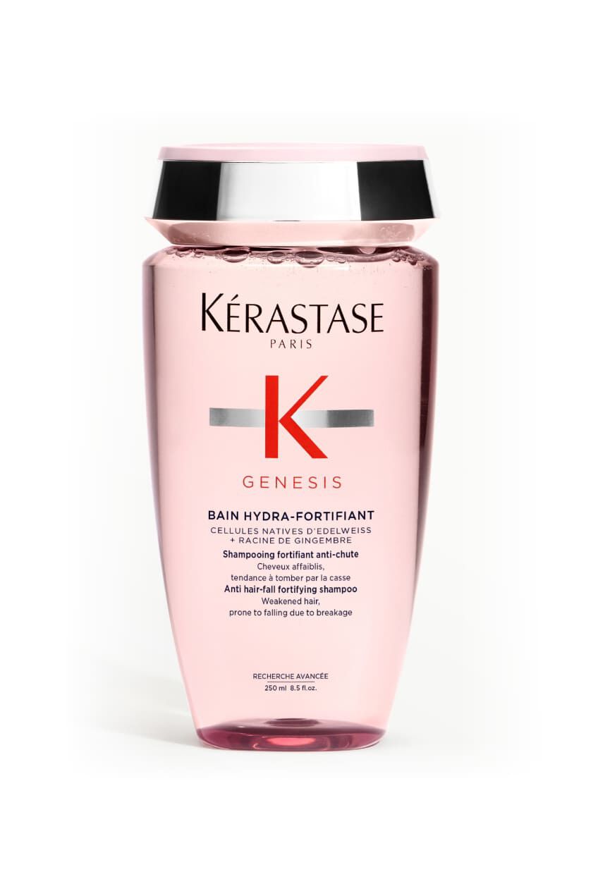 Bottiglia trasparente rosa dello shampoo Kerastase Genesis Bain Hydra-Fortifiant per capelli indeboliti, inclinata.