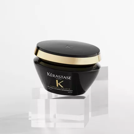 Vaso di crema Kerastase Chronologiste su supporti trasparenti, con un tappo dorato.