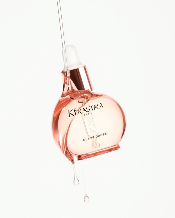 Flacone di siero Kerastase Paris Glaze Drops con gocce che cadono.