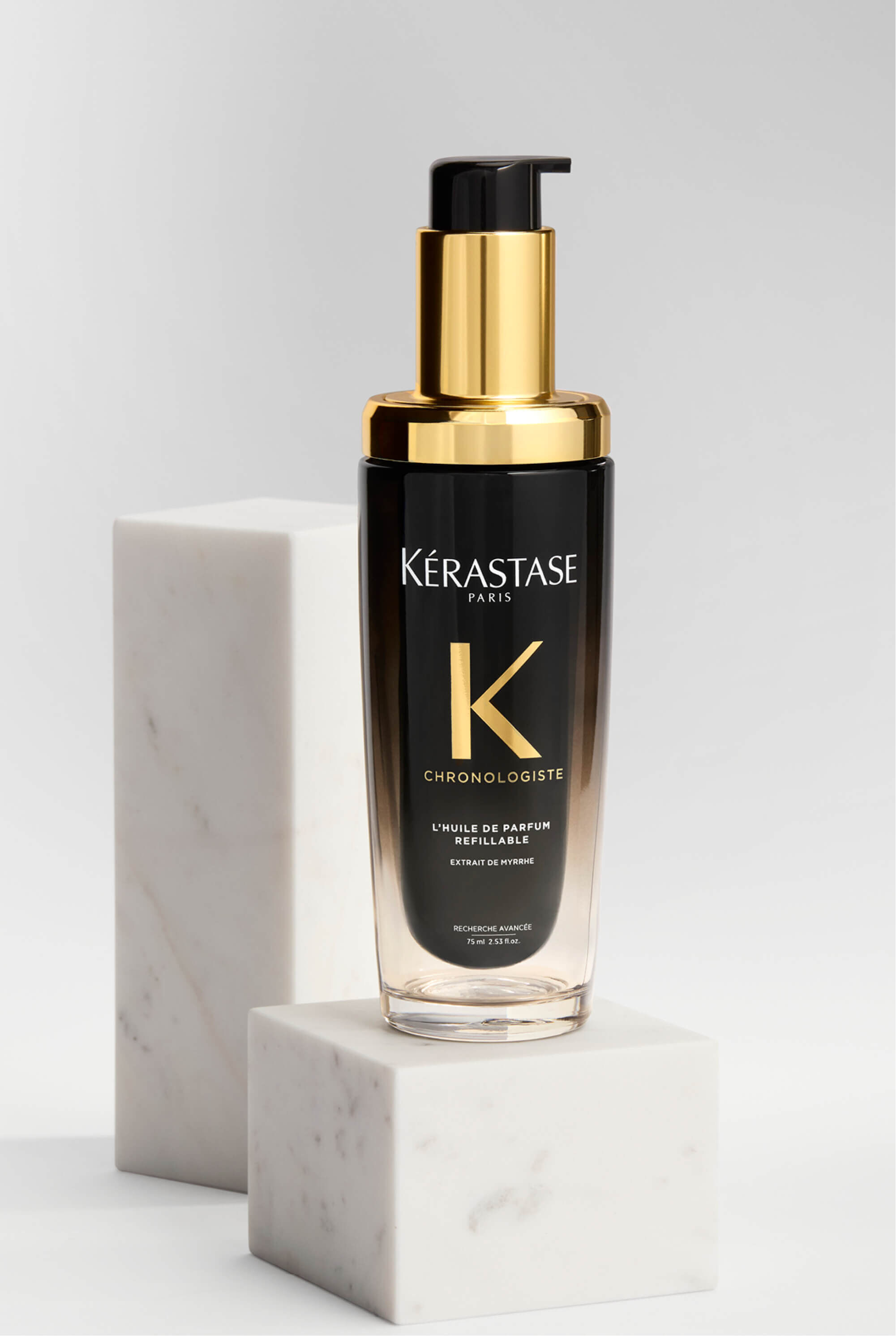 Flacone di Huile de Parfum Chronologiste su una piattaforma di marmo.​