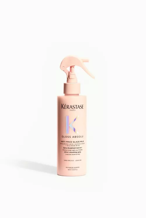 A pink spray bottle of Kerastase Gloss Absolu, labeled as an anti-frizz glaze milk. The bottle features a spray top and is designed for leave-in use.