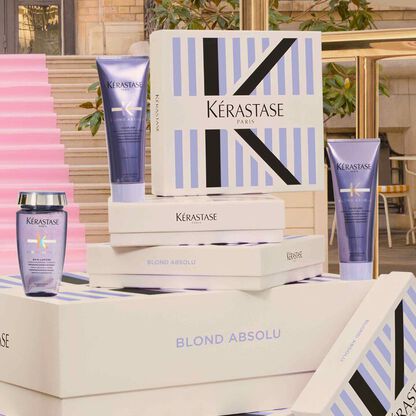 Prodotti Kerastase Blond Absolu in un elegante display su una scala rosa, evidenziando il glamour e la cura dei capelli.