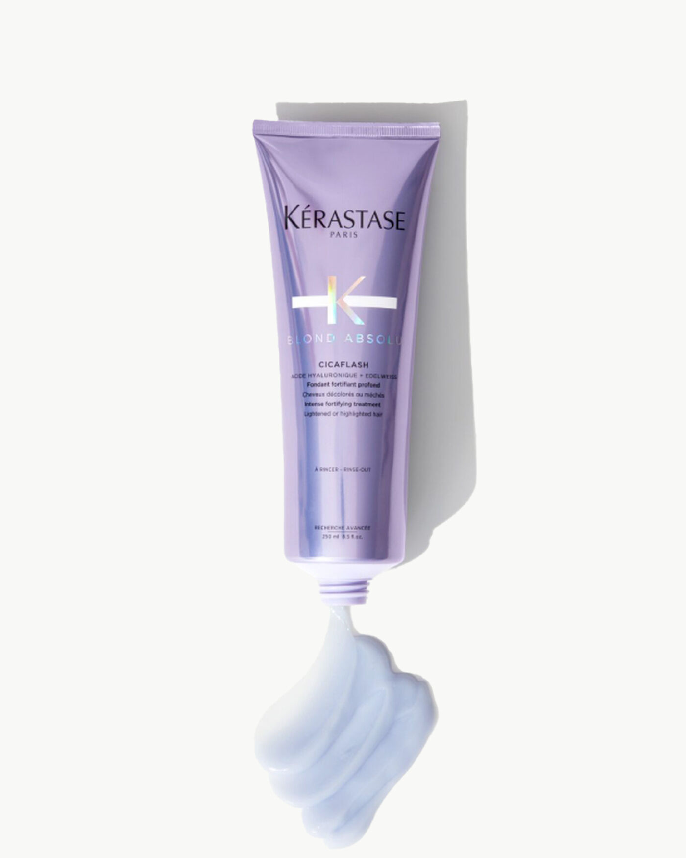 Un tubetto di prodotto per capelli Kerastase Blond Absole, con una consistenza cremosa e morbida di colore lilla che esce dal tappo.