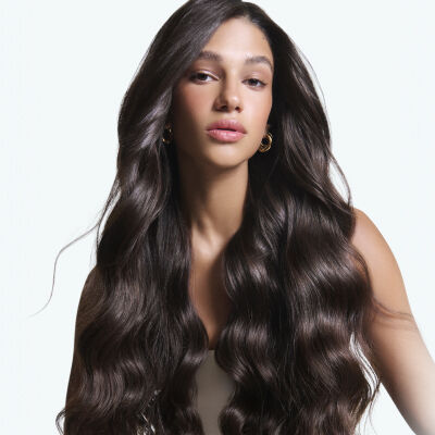 Ritratto di una donna con lunghi capelli castano scuro, lucidi e mossi.