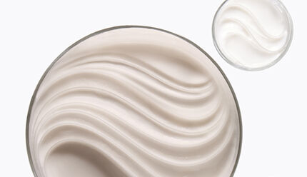 Due contenitori di crema liscia, uno grande e uno piccolo, posizionati su uno sfondo chiaro.