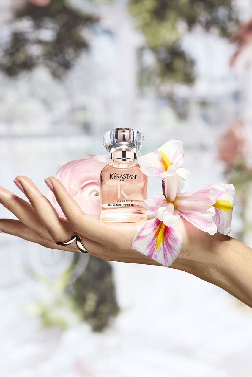Profumo Gloss Absolu, posato su una mano in un ambiente floreale che ricorda i suoi ingredienti