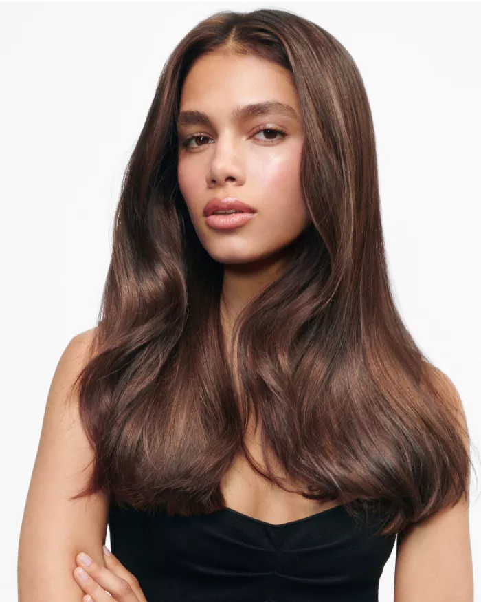Ritratto di una giovane donna con lunghi capelli castani fluenti, che indossa una maglietta nera e ha un'espressione serena.
