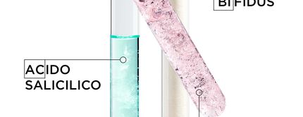 Tre provette contenenti ingredienti: a sinistra, un liquido azzurro con l'etichetta "Acido Salicilico"; al centro, una provetta con cristalli rosa etichettata "Bifidus"; a destra, un contenitore con polvere bianca etichettata "Piroct