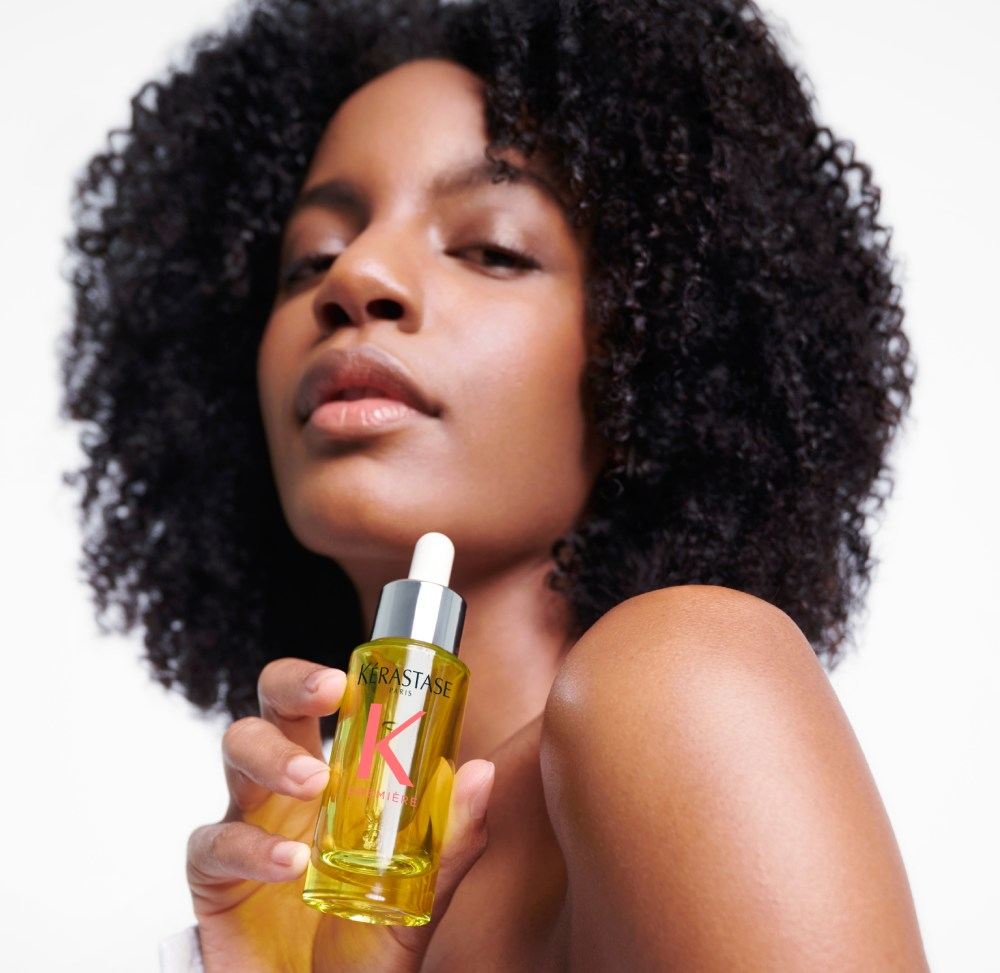 Ebonee Davis, con i suoi magnifici capelli ricci, mostra il miglior olio per capelli rovinati Première Huile Gloss Réparatrice.