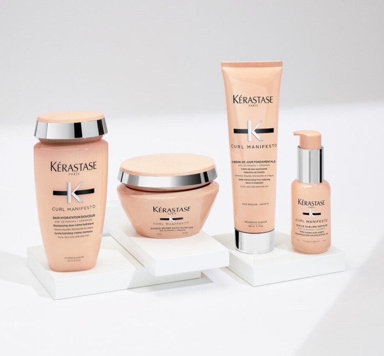 Quattro prodotti per capelli Kérastase della linea Curl Manifesto su supporti bianchi, con packaging in tonalità rosa.