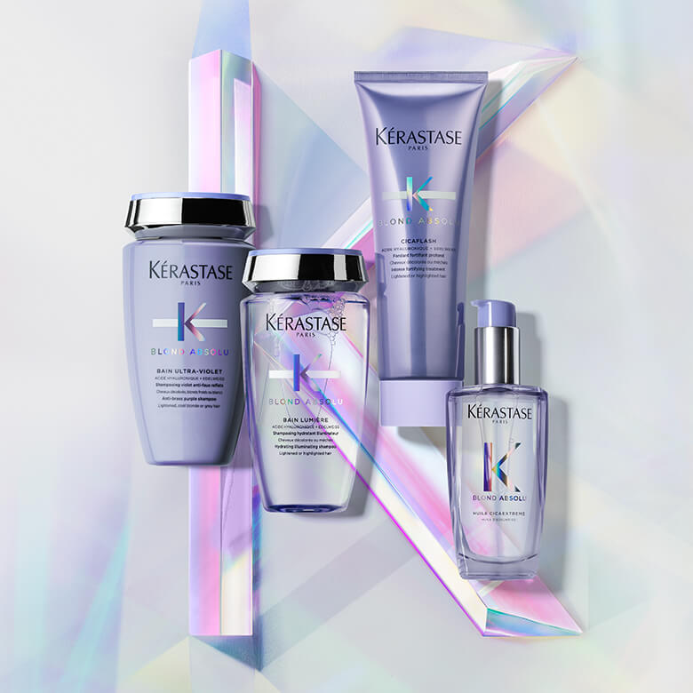 Quattro prodotti per capelli Kérastase della linea Blond Absolu, presentati su uno sfondo iridescente.