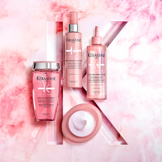 Tre prodotti per capelli Kérastase su uno sfondo rosa marmorizzato, evidenziando il marchio e la loro eleganza.