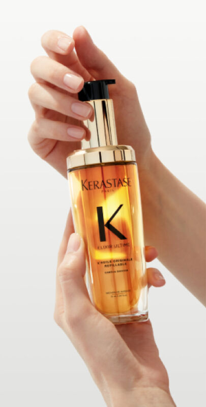 Flacone di olio per capelli Kerastase Elixir Ultime, tenuto in mano con eleganza su sfondo chiaro.