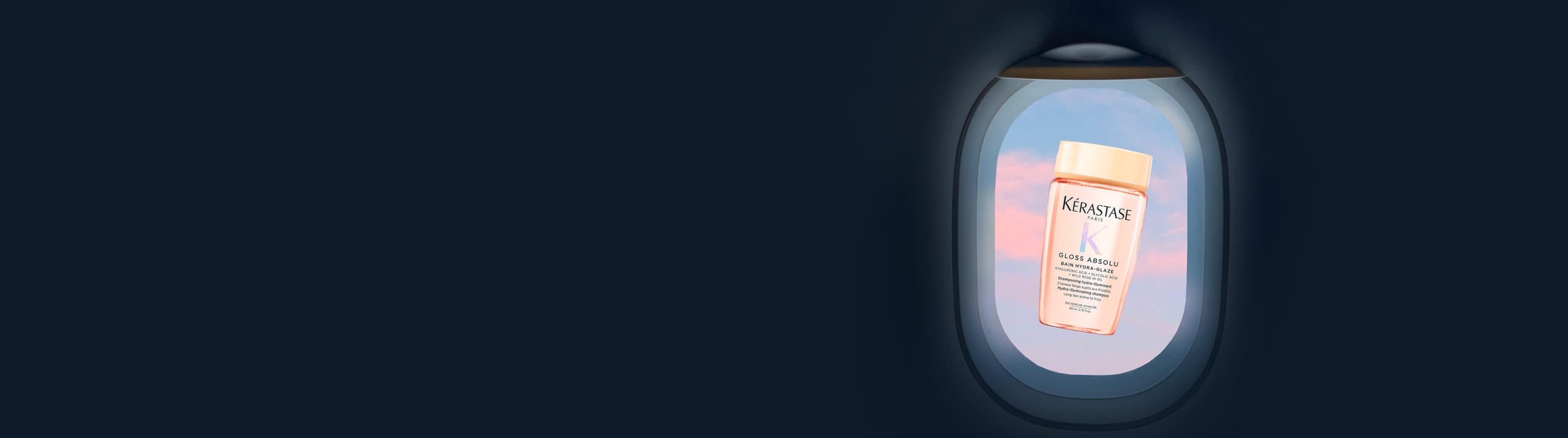 Flacone formato viaggio rosa traslucido di Kérastase Gloss Absolu Bain Hydra-Glaze, fluttuante al centro dell'oblò di un aereo, con cielo pastello rosa e blu.​
